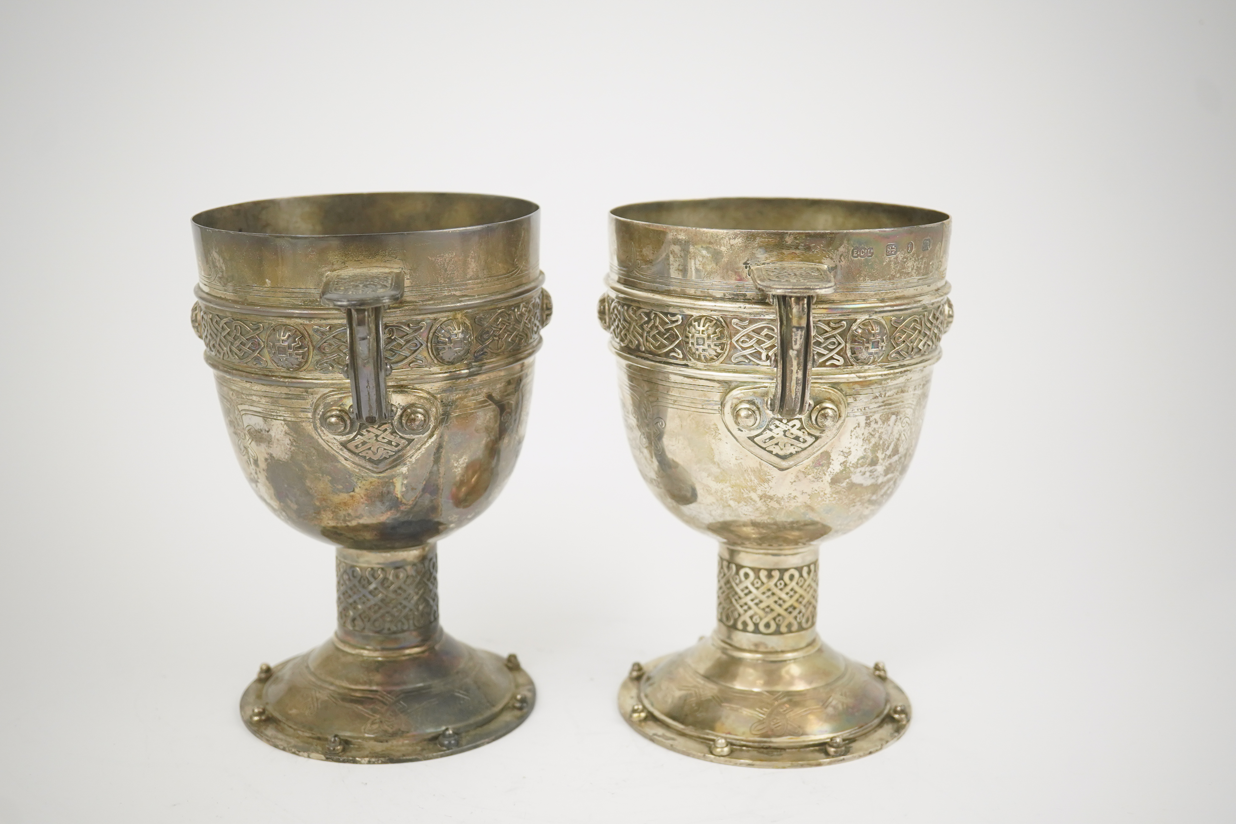 A pair of late Victorian Arts & Crafts Celtic style silver two handled presentation pedestal trophy cups, by Elkington & Co